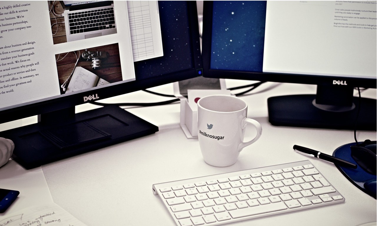 Two computer monitors, a cup of coffee, and a keyboard